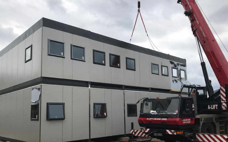 Modular building being lifted into place by crane